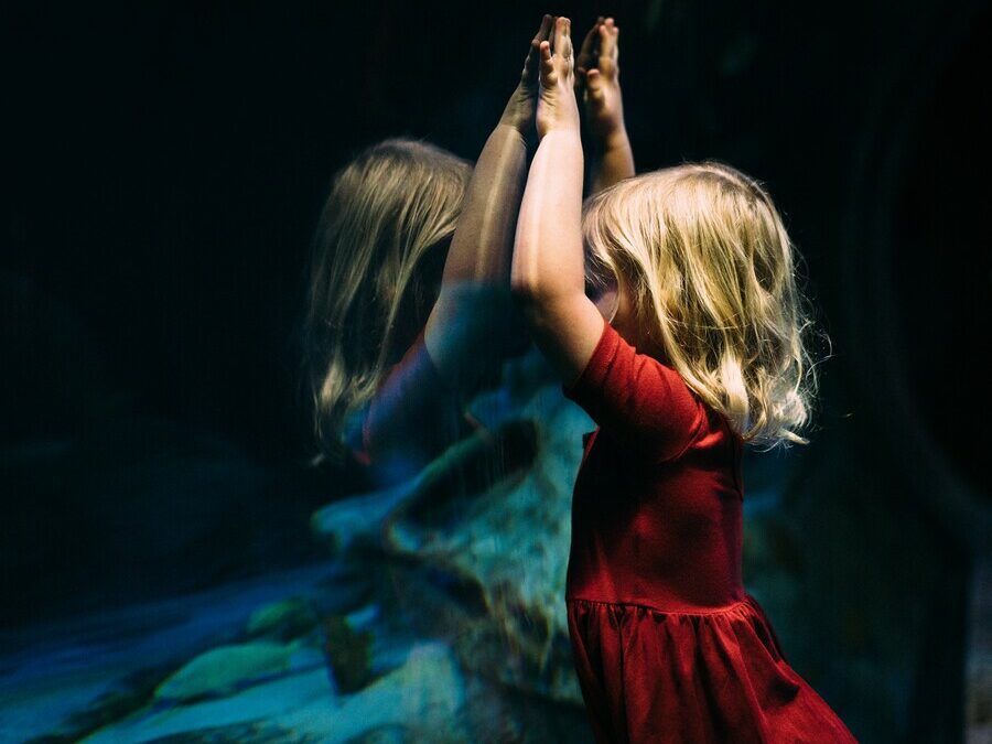 Petite fille blonde devant un miroir les bras levés